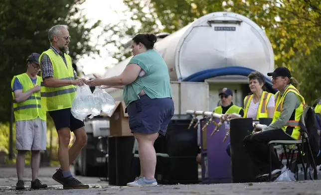 Workers hand out fresh water at a distribution site in the aftermath of Hurricane Helene Wednesday, Oct. 2, 2024, in Asheville, N.C. (AP Photo/Jeff Roberson)