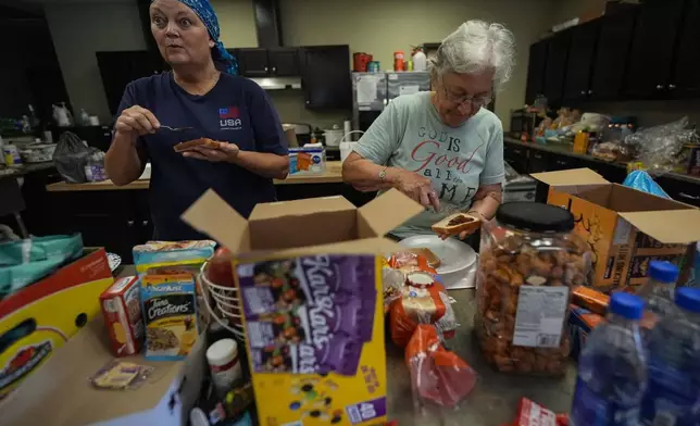 Volunteers prepare meals for firefighters and others at the volunteer fire station in the aftermath of Hurricane Helene, Thursday, Oct. 3, 2024, in Pensacola, N.C. (AP Photo/Mike Stewart)