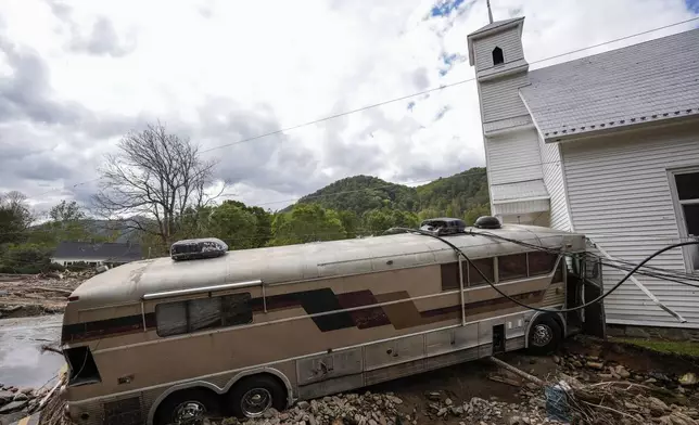 A bus pushed by flood waters rests against Laurel Branch Baptist church in the aftermath of Hurricane Helene, Thursday, Oct. 3, 2024, in Pensacola, N.C. (AP Photo/Mike Stewart)