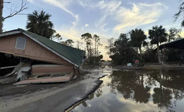 The sun sets over a flooded road and a collapsed building in Steinhatchee, Fla., Sunday, Sept. 29, 2024, in the aftermath of Hurricane Helene. (AP Photo/Kate Payne