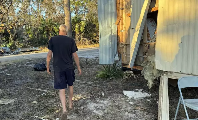 Dave Beamer walks past the partially destroyed trailer he's been living in, Sunday, Sept. 29, 2024, in Steinhatchee, Fla., after Hurricane Helene washed his home into a marsh. (AP Photo/Kate Payne)