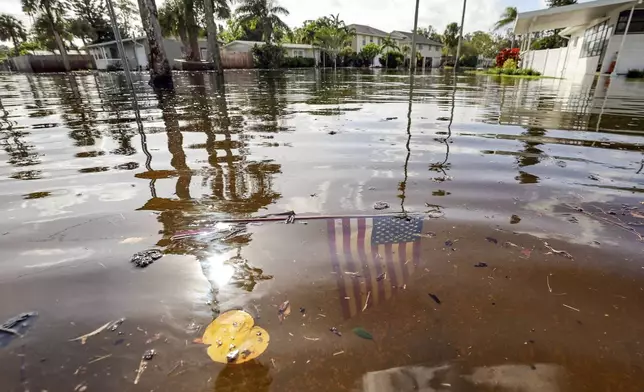 FILE - An American flag sits in floodwaters in the aftermath of Hurricane Helene in the Shore Acres neighborhood Sept. 27, 2024, in St. Petersburg, Fla. (AP Photo/Mike Carlson, File)