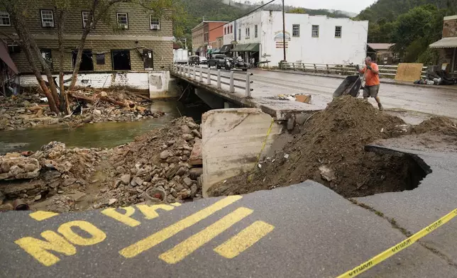 FILE - Len Frisbee dumps a wheelbarrow of dirt as he helps with clean up in the aftermath of Hurricane Helene, Oct. 1, 2024, in Hot Springs, N.C. (AP Photo/Jeff Roberson, File)