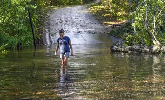 FILE - Teresa Elder walks through a flooded Sandy Cove Drive from Hurricane Helene, Sept. 27, 2024, in Morganton, N.C. (AP Photo/Kathy Kmonicek, File)