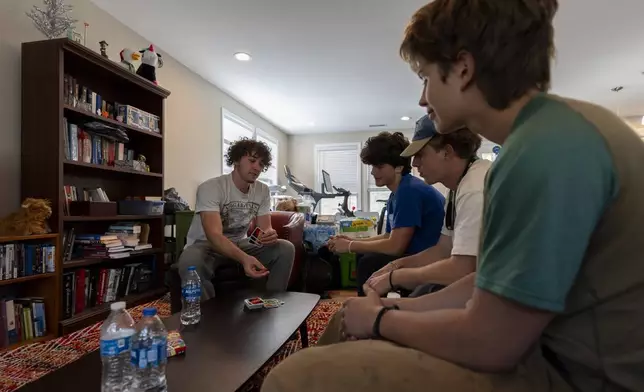 From left, high school seniors Ari Cohen, Nathaniel Durham, Abe Garry and Mason Cooke play a game of Uno in Cohen's living room, Friday, Oct. 18, 2024, in Asheville, N.C. (AP Photo/Stephanie Scarbrough)