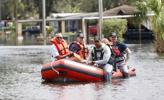 Hillsborough County fire and rescue use a boat to bring local residents to safety from their flooded homes on Thursday, Oct. 10, 2024, in Progress Village Community, Fla. (Jefferee Woo/Tampa Bay Times via AP)