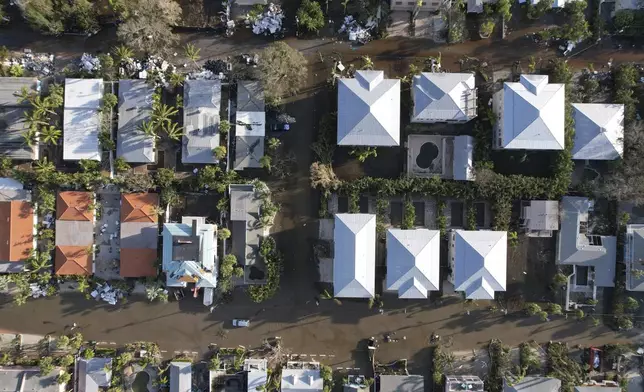 Flood waters recede after Hurricane Milton, on streets where piles of debris from Hurricane Helene flooding, sit outside many homes, in Siesta Key, Fla., Thursday, Oct. 10, 2024. (AP Photo/Rebecca Blackwell)