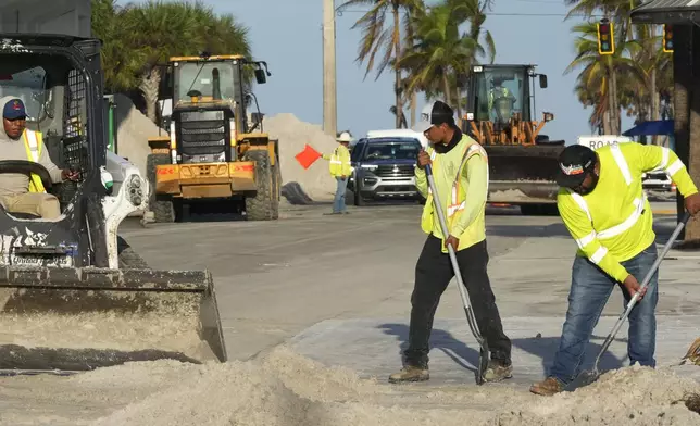 Public work employees remove sand from the roadways, that was pushed to the streets by Hurricane Milton, Friday, Oct. 11, 2024, in Fort Myers Beach, Fla. (AP Photo/Marta Lavandier)