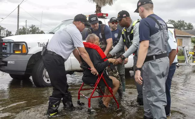 Hillsborough County fire and rescue assist local residents from their flooded homes on Thursday, Oct. 10, 2024, in Progress Village Community, Fla. (Jefferee Woo/Tampa Bay Times via AP)