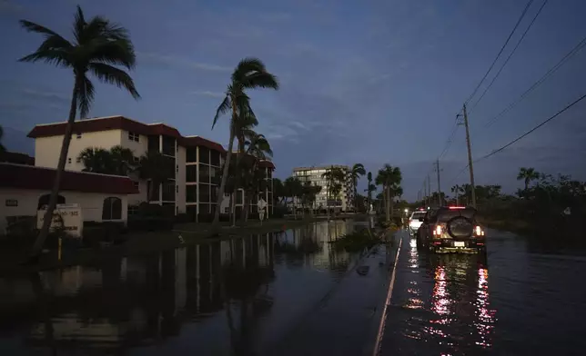 A car backs up after encountering deeper water on a flooded street in Siesta Key, Fla., following the passage of Hurricane Milton, Thursday, Oct. 10, 2024. (AP Photo/Rebecca Blackwell)