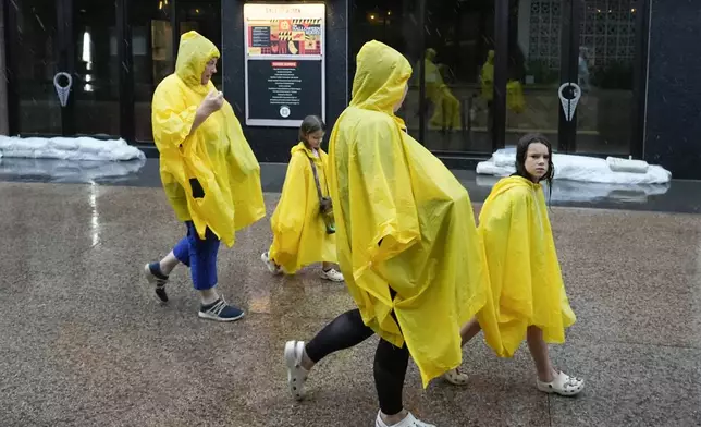 Tourists walk past a sandbagged store entrance as they exit the Disney Springs entertainment complex before the arrival of Hurricane Milton Wednesday, Oct. 9, 2024, in Lake Buena Vista, Fla. (AP Photo/John Raoux)