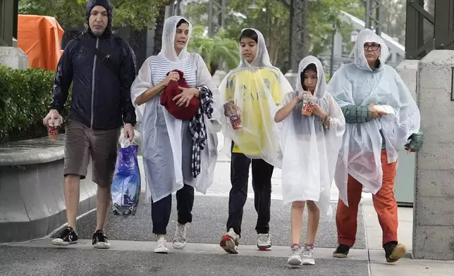 Tourists exit the Disney Springs entertainment complex before the arrival of Hurricane Milton, Wednesday, Oct. 9, 2024, in Lake Buena Vista, Fla. (AP Photo/John Raoux)