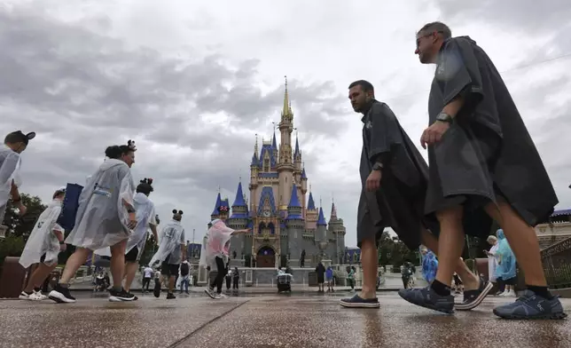 Guests weather early bands of rain from Hurricane Milton at the Magic Kingdom at Walt Disney World in Bay Lake, Fla., Wednesday, Oct. 9, 2024. (Joe Burbank/Orlando Sentinel via AP)