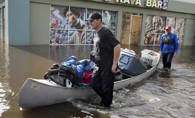 Resident along the Alafia river carry out their belongings by canoe through floodwaters from Hurricane Milton Friday, Oct. 11, 2024, in Lithia, Fla. (AP Photo/Chris O'Meara)