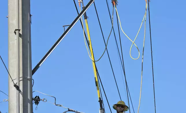 A lineman from Pike Corporation, of North Carolina, works on electrical wires damaged by Hurricane Milton, Sunday, Oct. 13, 2024, in Valrico, Fla. (AP Photo/Chris O'Meara)