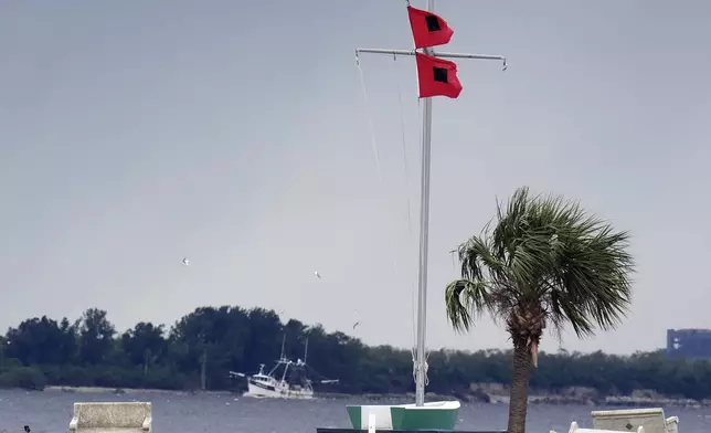 A shrimping boat makes her way back to port as hurricane flags fly at the Davis Islands Yacht Club, Monday, Oct. 7, 2024, in Tampa, Fla. (AP Photo/Chris O'Meara)