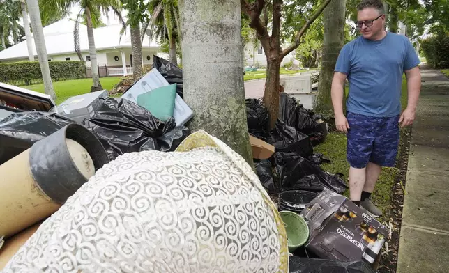 Scott Joyner looks at damaged items he removed from his garage following flooding caused by Hurricane Helene, Tuesday, Oct. 8, 2024, in Punta Gorda, Fla., as residents of of the historic neighborhood are now bracing for possible storm surge from Hurricane Milton. (AP Photo/Marta Lavandier)