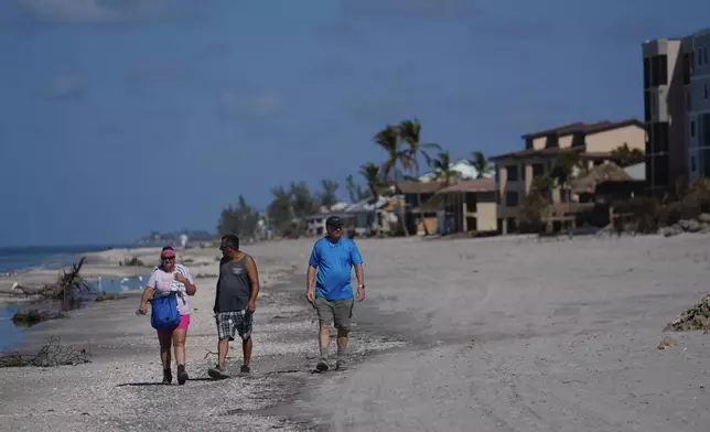 A property owner is accompanied by friends as he walks along the beach on his way to survey damage to his three properties, following the passage of Hurricane Milton, on Manasota Key, in Englewood, Fla., following the passage of Hurricane Milton, Sunday, Oct. 13, 2024. (AP Photo/Rebecca Blackwell)