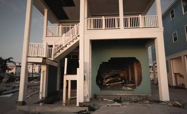 A boat is seen through a broken wall on the ground floor of a stilted home on Manasota Key, Fla., following the passage of Hurricane Milton, Saturday, Oct. 12, 2024. (AP Photo/Rebecca Blackwell)