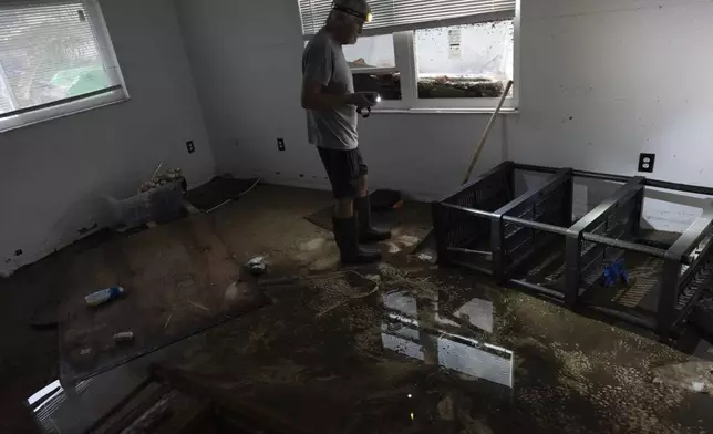 Robert Turick, 68, stands in remaining water in one of his home's bedrooms, where the high water mark from Hurricane Milton can be seen on the wall, in Englewood, Fla., Friday, Oct. 11, 2024. A small positive, said Turick, is that he hadn't yet begun repairs after Hurricane Helene brought 3-foot flood waters, and he, his dog, and his daughter were staying elsewhere when Milton flooded his home around to 5 feet. During Helene, they had to climb out his daughter's bedroom window to flee rising surge waters, after the front door became blocked. (AP Photo/Rebecca Blackwell)