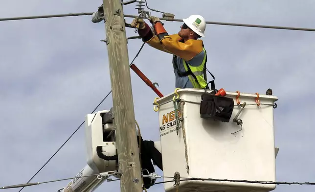 A linesman contractor for Duke Energy works on power lines along Forest City Road in Orlando. Friday, Oct. 11, 2024. As of Friday morning, 2.2 million Floridians were reported to still be without power. (Joe Burbank/Orlando Sentinel via AP)