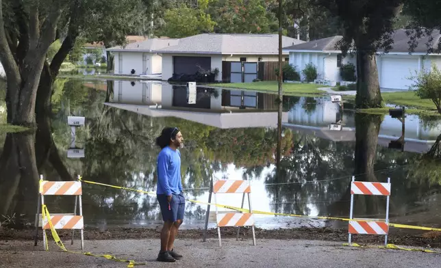 A Spring Oaks resident checks out the rising floodwaters from the Little Wekiva River on Spring Oaks Blvd. in his neighborhood in Altamonte Springs, Fla., Friday, Oct. 11, 2024. Central Florida rivers are forecast to crest in the coming days because of the excessive rainfall from Hurricane Milton. (Joe Burbank/Orlando Sentinel via AP)