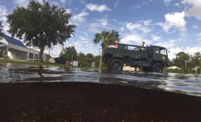 Panellas County Sheriff officials escort residents into the Tarpon Woods neighborhood as people return to their homes following Hurricane Milton, Friday, Oct. 11, 2024, in Palm Harbor, Fla. (AP Photo/Julio Cortez)