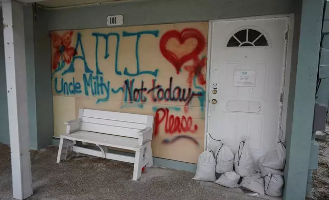 Boards on the window of a store display a message ahead of the arrival of Hurricane Milton, in Bradenton Beach on Anna Maria Island, Fla., Tuesday, Oct. 8, 2024. (AP Photo/Rebecca Blackwell)