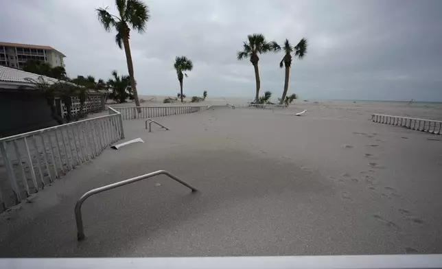 Only handrails are visible after a beachfront swimming pool was inundated with sand displaced by Hurricane Milton, at Sea Villas condominiums in Venice, Fla., Friday, Oct. 11, 2024. (AP Photo/Rebecca Blackwell)