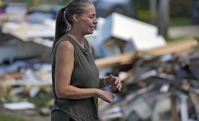 Brooke Carstensen sands near debris from Hurricanes Helene and Milton outside her home Sunday, Oct. 13, 2024, in Tampa, Fla. (AP Photo/Chris O'Meara)