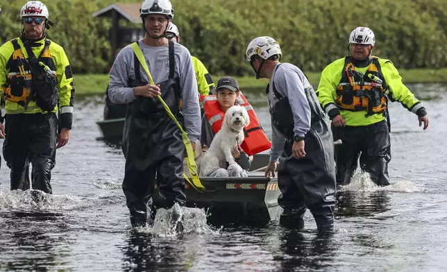 Amy Bishop is evacuated from her home by Pasco County Fire and Rescue and Sheriff's Office teams as waters rise in her neighborhood after Hurricane Milton caused the Anclote River to flood, Friday, Oct. 11, 2024, in New Port Richey, Fla. (AP Photo/Mike Carlson)