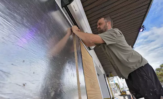 Rob Menard, owner of Reefers Social Club, finishes putting up boards and tape over windows Monday, Oct. 7, 2024, in Clearwater Beach, Fla., ahead of the possible arrival of Hurricane Milton. (AP Photo/Chris O'Meara)