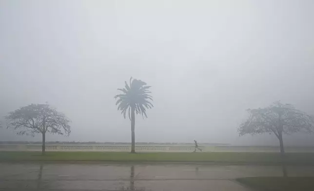 A jogger trots as rain falls ahead of the arrival of Hurricane Milton, Wednesday, Oct. 9, 2024, in Tampa, Fla. (AP Photo/Julio Cortez)