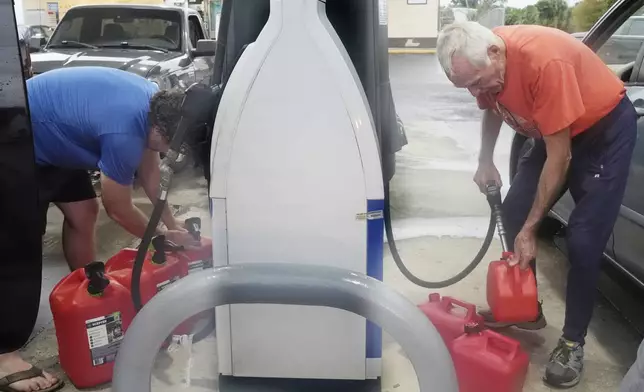 Don Hallenbeck, right, fills gas tanks as he prepares to stay in his home in advance of Hurricane Milton, Wednesday, Oct. 9, 2024, in Port Charlotte, Fla. (AP Photo/Marta Lavandier)