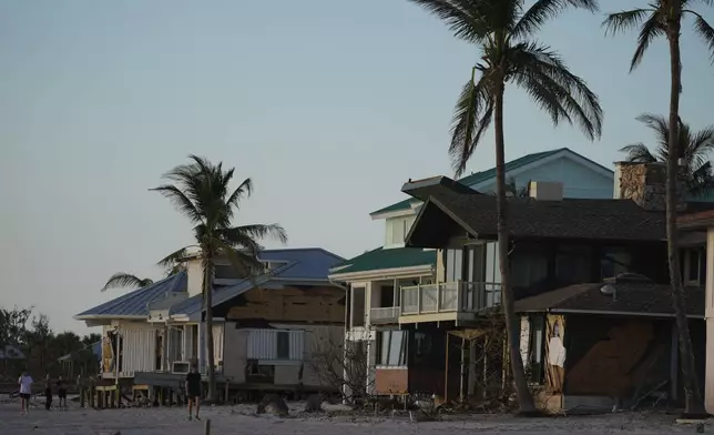 People survey damage to beachfront homes, many of which had their ground floor level washed out, following Hurricane Milton, on Manasota Key, Fla., Saturday, Oct. 12, 2024. (AP Photo/Rebecca Blackwell)