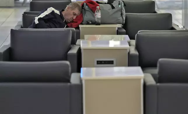 A passenger sleeps at the Tampa International Airport Tuesday, Oct. 8, 2024, in Tampa, Fla., after most flights were canceled due to the possible arrival of Hurricane Milton. (AP Photo/Chris O'Meara)