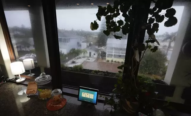 Neighboring homes, a pile of debris and a garage damaged in Hurricane Helene, are seen from the third-floor of the home where Christian Burke, his mother and aunt will ride out Hurricane Milton, in Gulfport, Fla., Wednesday, Oct. 9, 2024. Burke, who said his engineer father built the concrete home to withstand a Category 5 hurricane, expects his raised ground floor to flood severely, but for the building to remain standing. (AP Photo/Rebecca Blackwell)