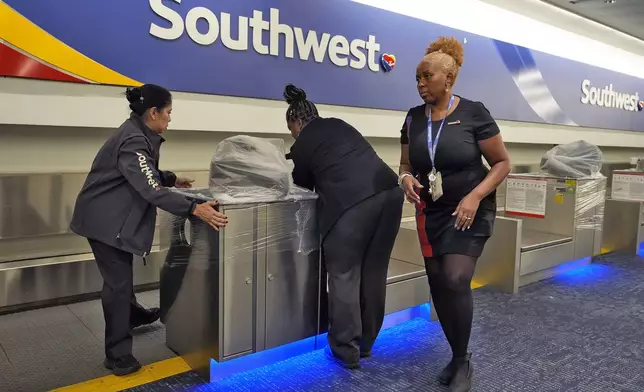 Southwest Airlines employees cover the ticket counters with plastic wrap just before Tampa International Airport was closing due to the possible arrival of Hurricane Milton Tuesday, Oct. 8, 2024, in Tampa, Fla. (AP Photo/Chris O'Meara)