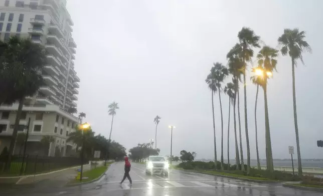 A person walks under light rain ahead of the arrival of Hurricane Milton, Wednesday, Oct. 9, 2024, in Tampa, Fla. (AP Photo/Julio Cortez)