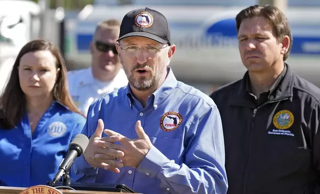 Kevin Guthrie, Florida Division of Emergency Management, speaks during a news conference at a newly opened fuel depot Saturday, Oct. 12, 2024, in Plant, Fla. Looking on are Florida Attorney General Ashley Moody, left, and Gov. Ron DeSantis, right. (AP Photo/Chris O'Meara)