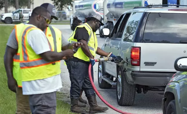 Fuel distribution workers fill cars at a depot, Saturday, Oct. 12, 2024, in Plant City, Fla. Gas stations are slow to reopen after the effects of Hurricane Milton. (AP Photo/Chris O'Meara)