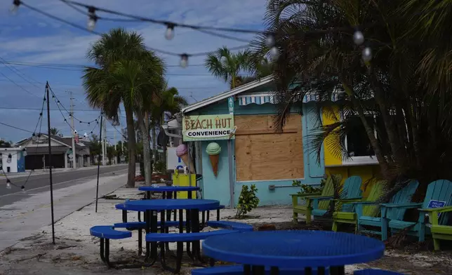 A boarded up business stands beside a deserted street in an evacuation zone, ahead of the arrival of Hurricane Milton, in Anna Maria, Fla., on Anna Maria Island, Tuesday, Oct. 8, 2024. (AP Photo/Rebecca Blackwell)