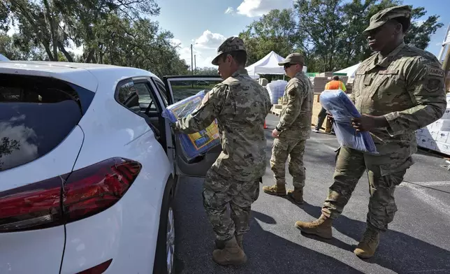 Members of the Florida Air National Guard load supplies into the cars of residents displaced by Hurricane Milton, Sunday, Oct. 13, 2024, at the Hillsborough Community College campus in Brandon, Fla. (AP Photo/Chris O'Meara)