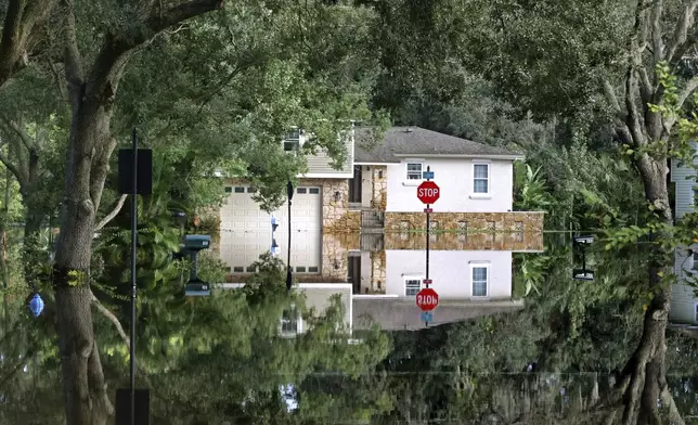 A home on Little Wekiva Road in the Spring Oaks neighborhood in Altamonte Springs, Fla is reflected in the floodwaters from the Little Wekiva River, Friday, Oct. 11, 2024. Central Florida rivers are forecast to crest in the coming days because of the excessive rainfall from Hurricane Milton. (Joe Burbank/Orlando Sentinel via AP)