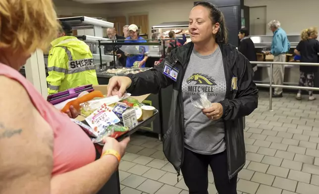 Pasco Schools administrator Jill Cortier speaks with an evacuee during a meal service at a hurricane shelter at River Ridge Middle/High School in preparation for Hurricane Milton, Wednesday, Oct. 9, 2024, in New Port Richey, Fla. (AP Photo/Mike Carlson)