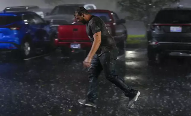 Chris Nation, of Commerce, Ga., skids on puddles in the parking lot of the hotel where he's riding out Hurricane Milton, Wednesday, Oct. 9, 2024, in Tampa, Fla. Nation, who works for a towing company, was deployed to Florida to aid in the aftermath of the storm. (AP Photo/Julio Cortez)