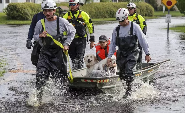 Amy Bishop is evacuated from her home by Pasco County Fire and Rescue and Sheriff's Office teams as waters rise in her neighborhood after Hurricane Milton caused the Anclote River to flood, Friday, Oct. 11, 2024, in New Port Richey, Fla. (AP Photo/Mike Carlson)