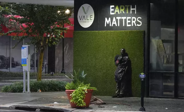 Melvin Lee HIcks, who is homeless, wears a trash bag to protect against wind-driven rain, as he stands on a deserted street in downtown Tampa, Fla., during the approach of Hurricane Milton, Wednesday, Oct. 9, 2024. (AP Photo/Rebecca Blackwell)