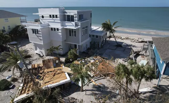 A house swept off its foundation and split in half by Hurricane Milton is seen alongside stilted homes, which suffered damaged to their ground floor storage levels, but remained standing, on Manasota Key, in Englewood, Fla., Sunday, Oct. 13, 2024. (AP Photo/Rebecca Blackwell)