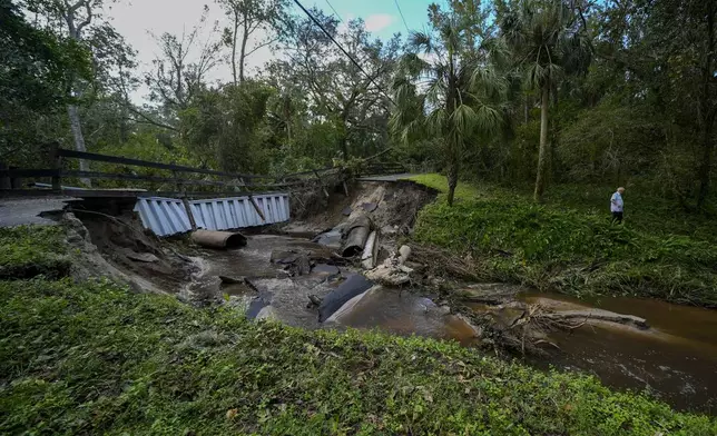 Del Ockey, a seasonal Florida resident from Canada, walks near the damaged bridge to his property from Hurricane Milton, Friday, Oct. 11, 2024, in Riverview, Fla. (AP Photo/Julio Cortez)